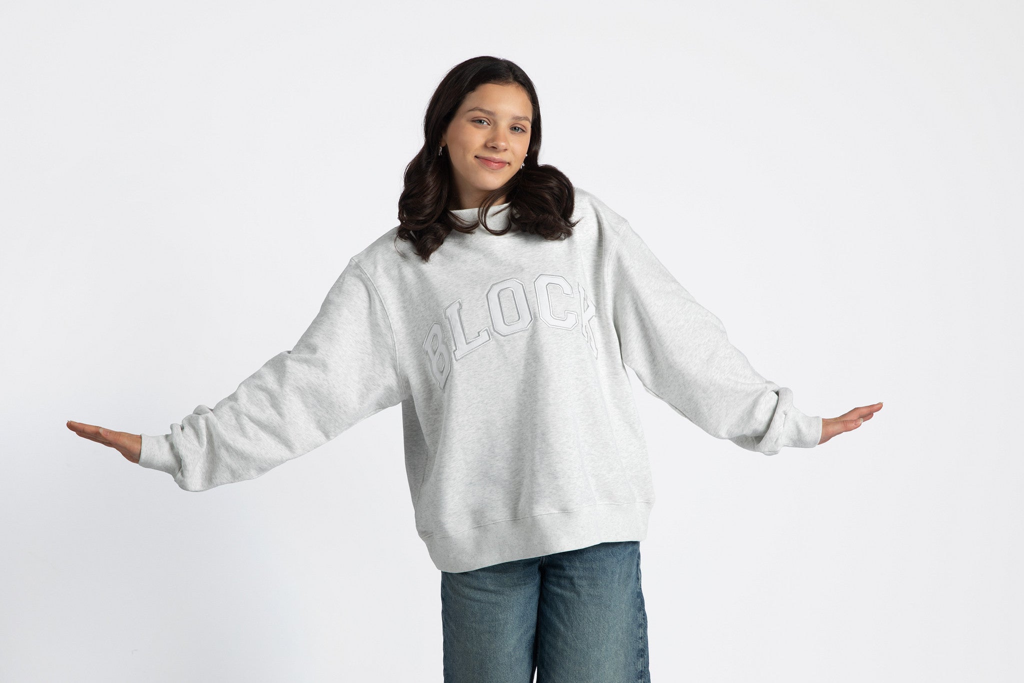 Girl wearing a gray sweatshirt with 'BLOCK' in tackle twill in white lettering