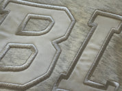 Close-up of textured fabric with embroidered letters on a light gray background of a volleyball sweatshirt