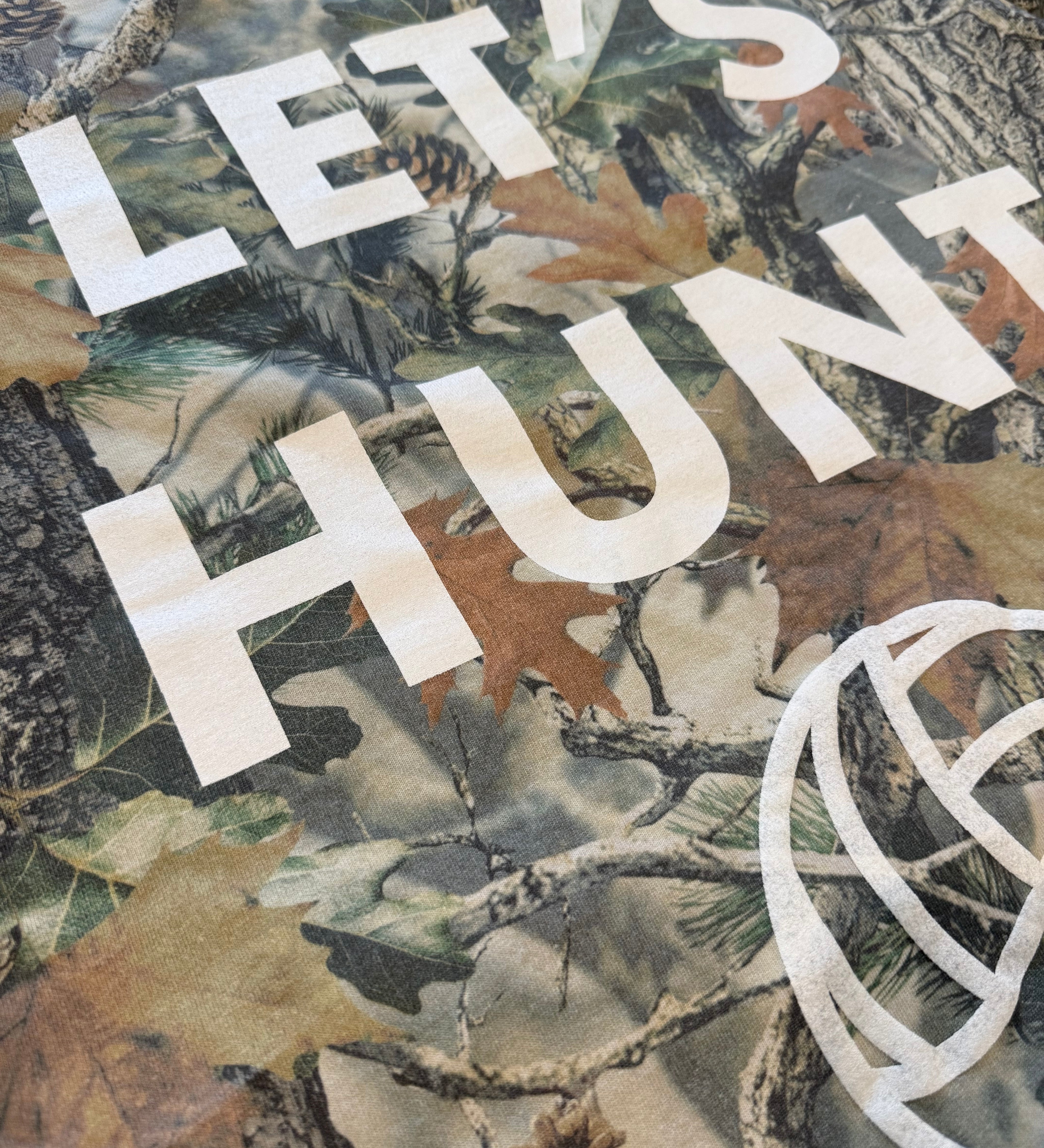 Woodland camouflage pattern with white text 'LET'S HUNT' and a volleyball on a t-shirt