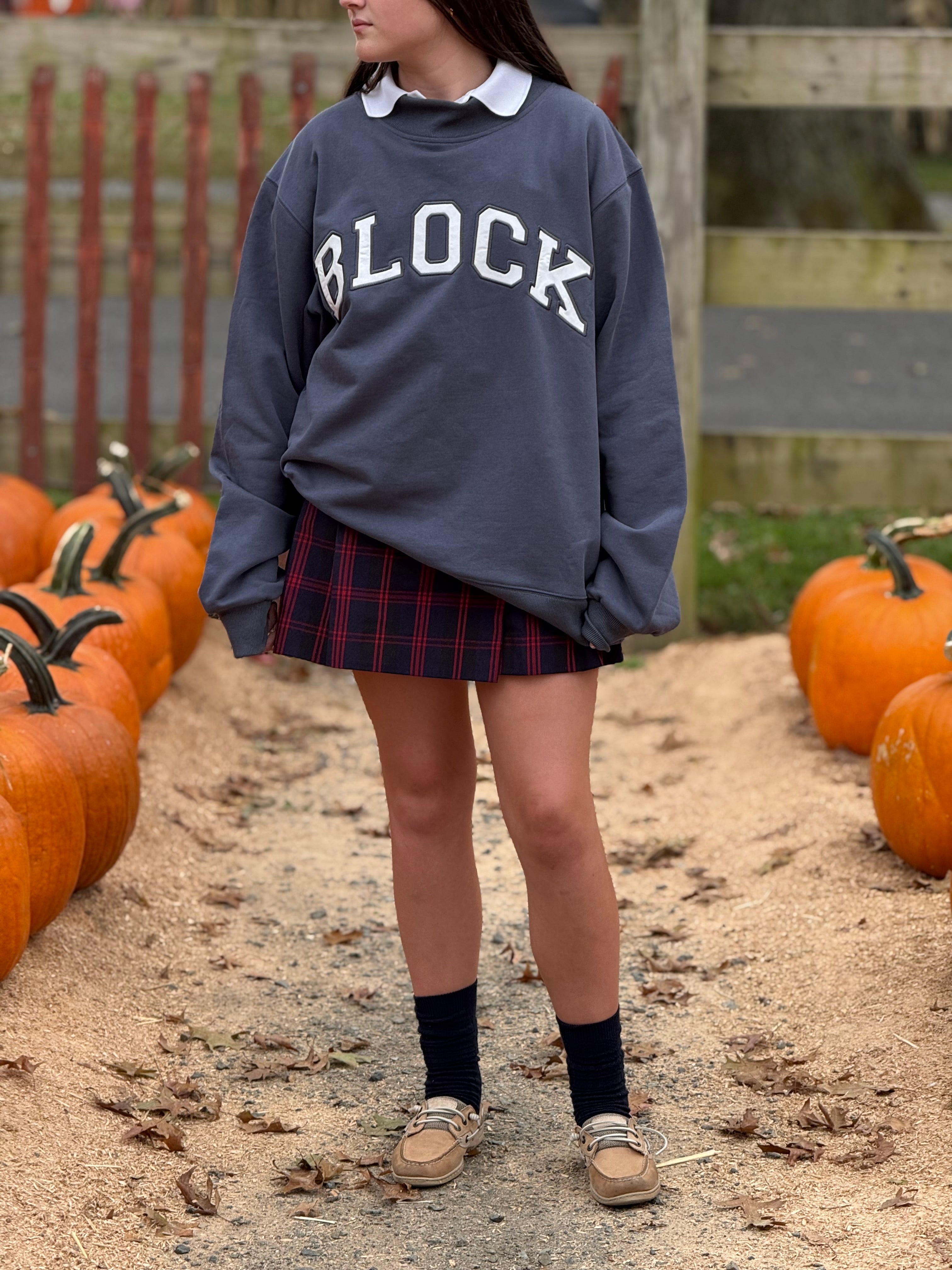 Woman wearing a 'BLOCK' volleyball sweatshirt in a fall setting