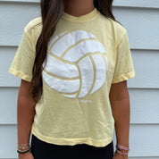 Woman wearing a yellow volleyball t-shirt with a white logo on a light background